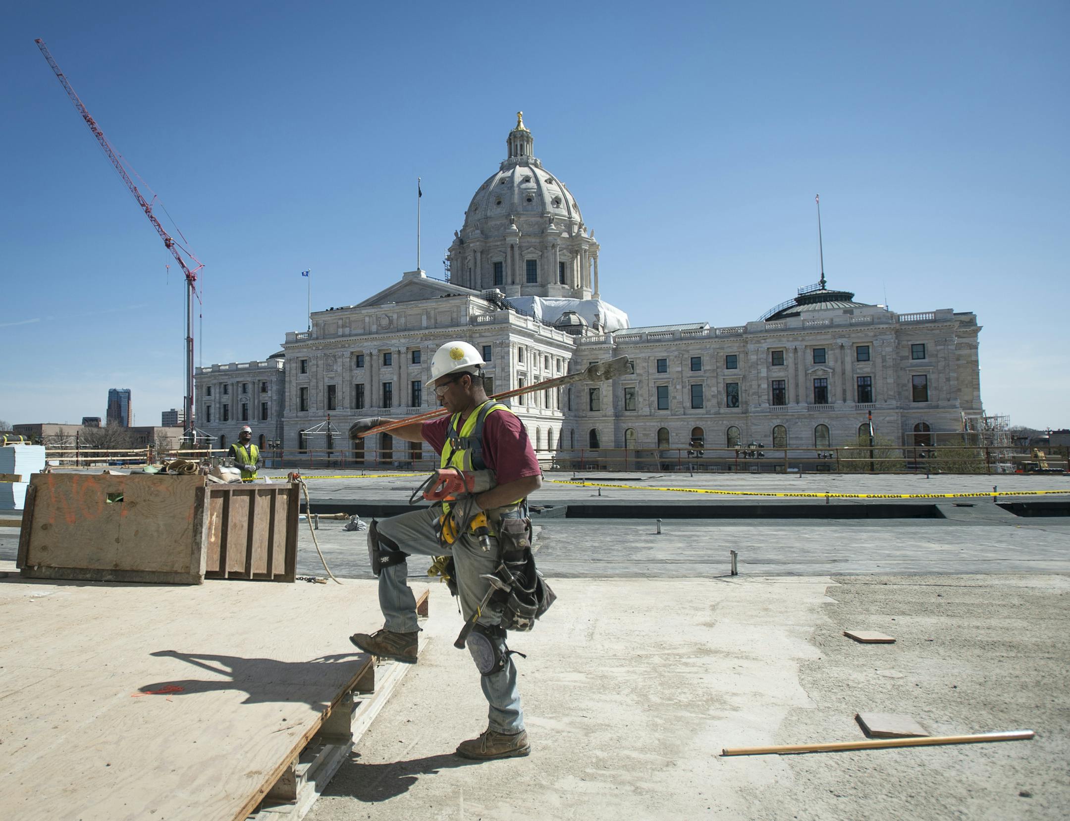 Jerome Flemming, a carpenter, carries a grizzly bar over his shoulder as he walks along the location of a future outdoor plaza at the Senate office building in St. Paul, Minn., Tuesday, April 14, 2015. Senate Democrats included money in a state budget bill this week to start leasing the $90 million facility for its expected opening next year. The tab is $13 million for 2016 and 2017 and about $8 million a year thereafter. (Aaron Lavinsky/Star Tribune via AP) MANDATORY CREDIT; ST. PAUL PIONEER PR