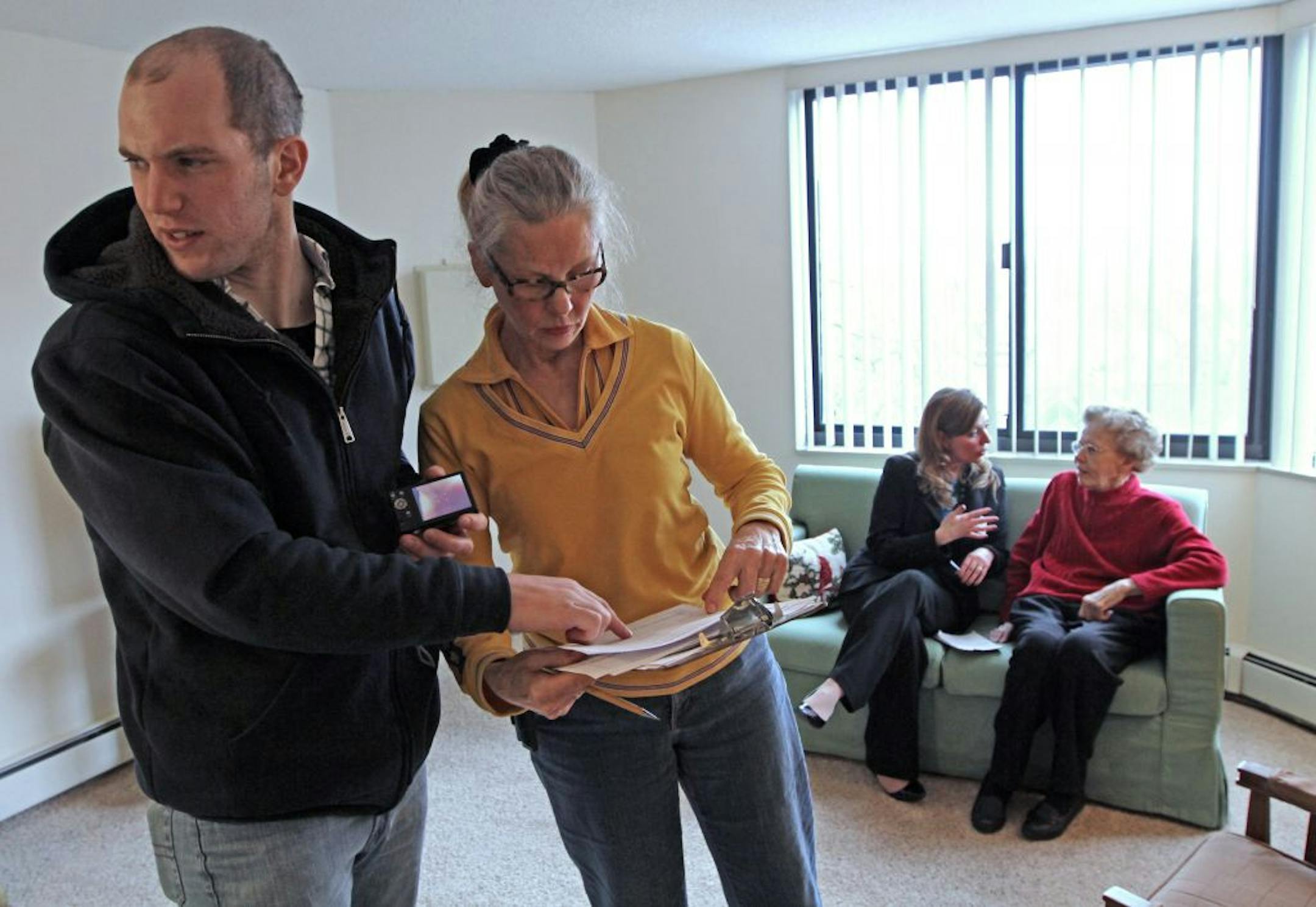 Jef De Smet and Sonya Anderson reviewed notes on Joyce Thompson, an Augustana Apartments resident and Anderson's cousin. Sitting with Thompson is Augustana's Aimee Robertson.