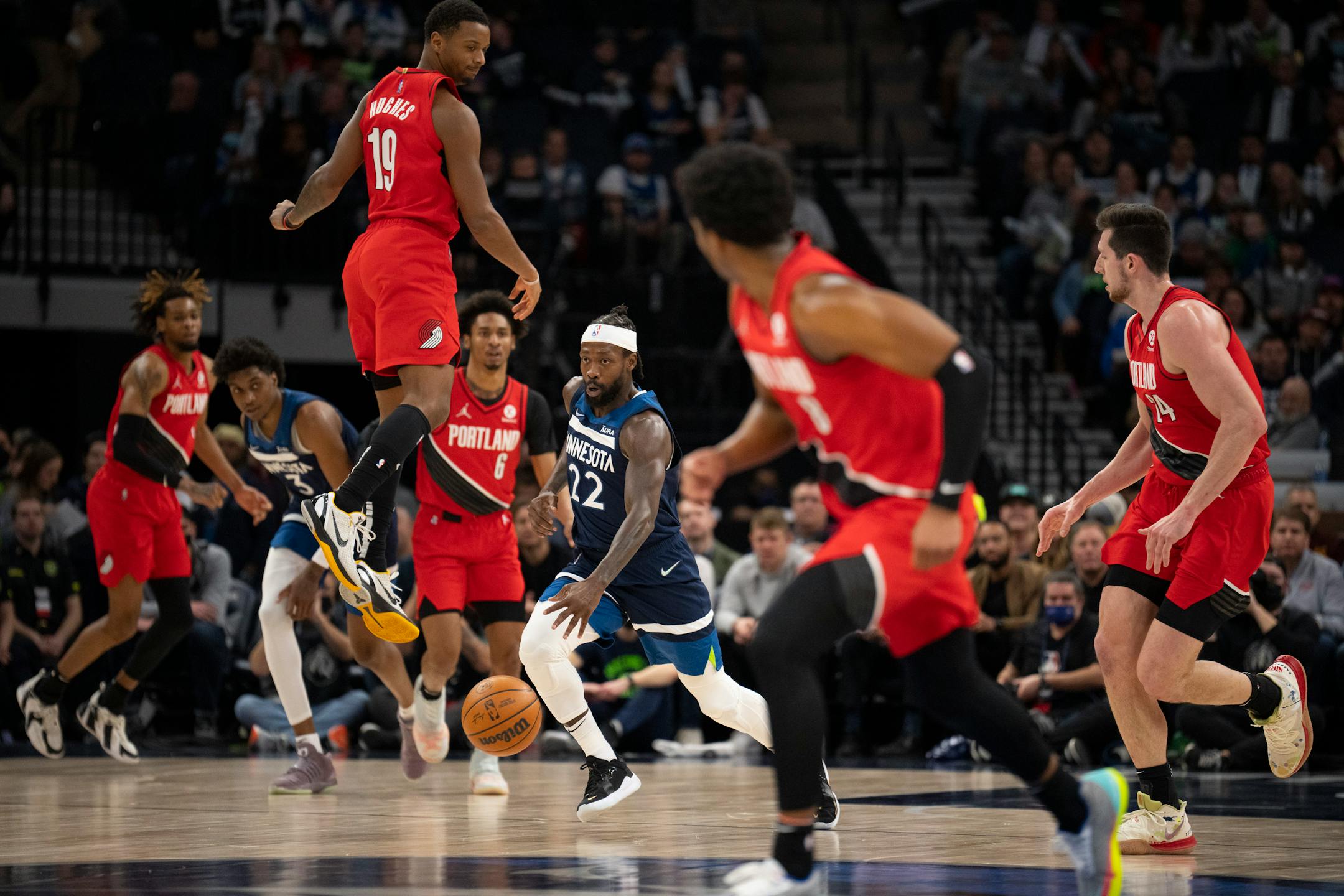Minnesota Timberwolves guard Patrick Beverley (22) dribbled past an airborne Portland Trail Blazers forward Elijah Hughes (19) in the first quarter.