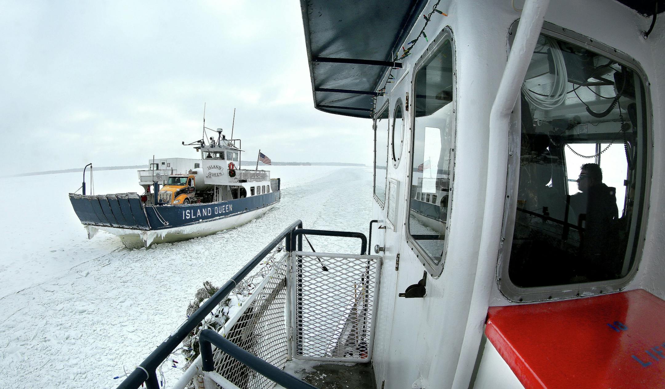 t1.5.18 Bob King -- 010618.N.DNT.FERRYc1 -- The Island Queen ferry (left) pulls over to one side of the channel to let the Nichevo II, piloted by Captain Steve Miller (right), pass on the way from Bayfield to Madeline Island Friday morning. Friday was the last day of ferry service to the island due to heavy ice buildup on Lake Superior. Bob King / rking@duluthnews.com