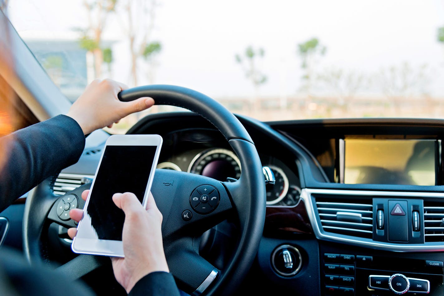 Female driver texting on mobile phone while driving.