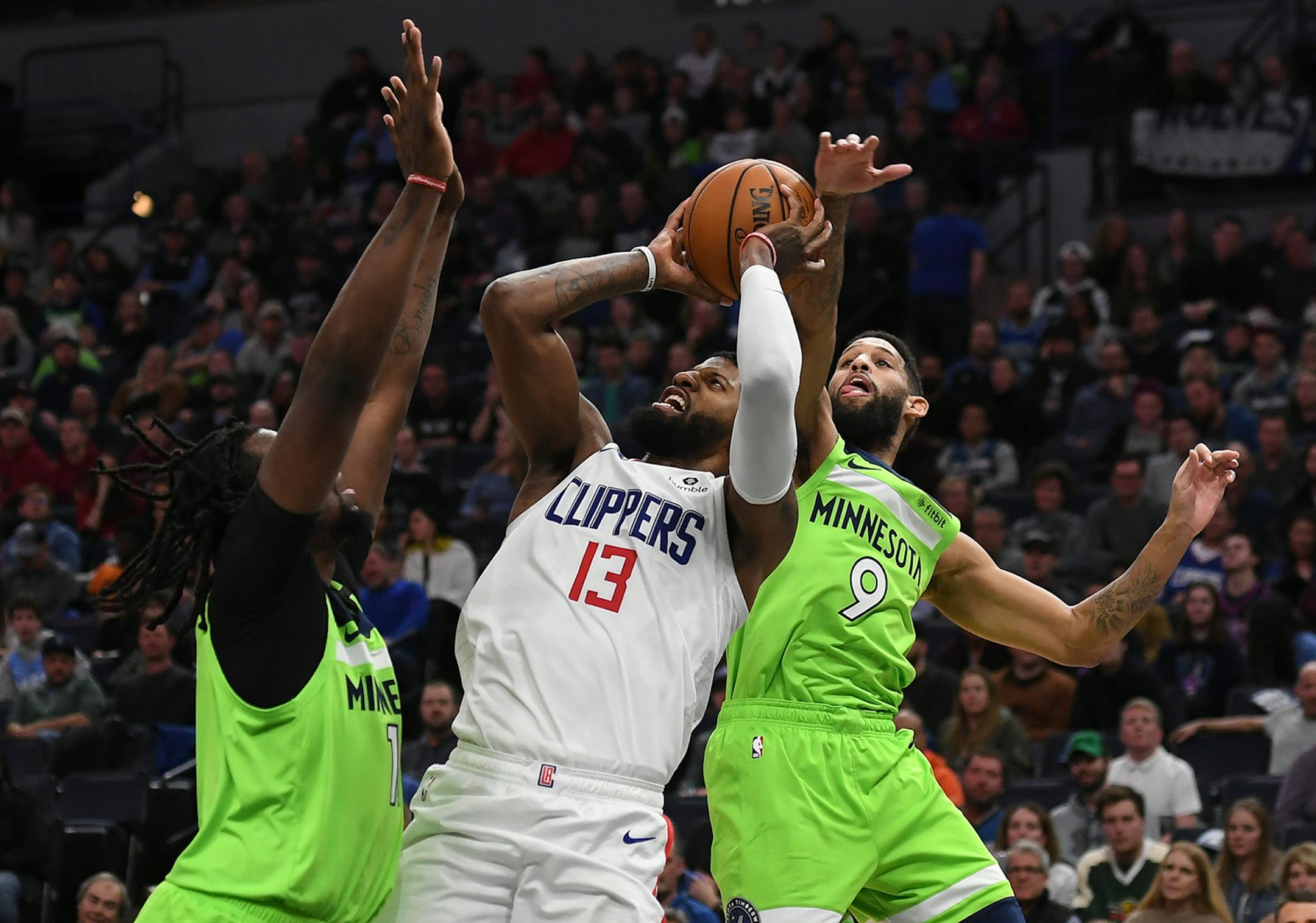 Minnesota Timberwolves center Naz Reid (11) and guard Allen Crabbe (9) shut down a scoring attempt by LA Clippers guard Paul George (13) in the second half.