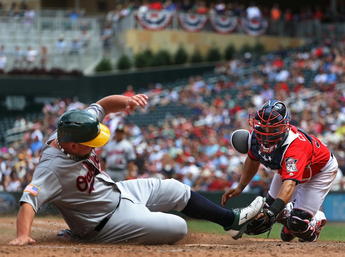 Billy Butler(16) scored at home before catcher Juan Centeno(37) could apply the tag in the seventh inning making the score 3-1.[At the Twins game against the A's at Target Field on 7/04/16. Richard Tsong-taatarii@startribune.com