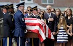 Vice President Joe Biden, accompanied by his family, holds his hand over his heart as he watches an honor guard carry a casket containing the remains 