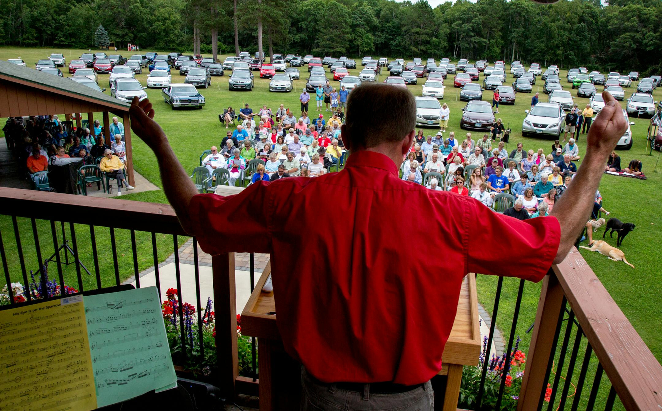 Pastoral Intern Kurt Hagestuen leads the Crosslake Lutheran Church outdoor service in prayer before communion. ] COURTNEY PEDROZA • courtney.pedroza@startribune.com; Crosslake Lutheran Church outdoor service; Crosslake, MN; Service held in an old outdoor movie theater lot; July 23, 2017 Sunday