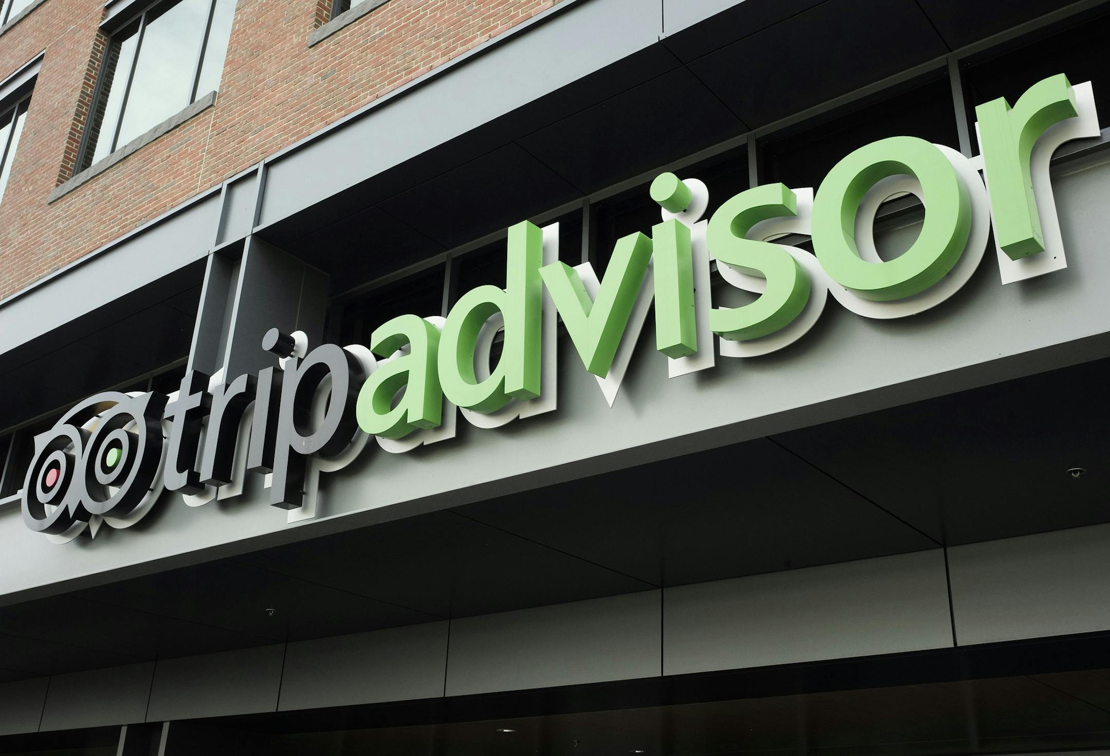 The company logo for the travel website TripAdvisor hangs at the company's headquarters, Thursday, Nov. 2, 2017, in Needham, Mass. TripAdvisor says it has changed its rules about reviews that contain allegations of rape or other crimes, following a published report that quoted several users who said such postings were deleted. (AP Photo/Steven Senne) ORG XMIT: MASR401
