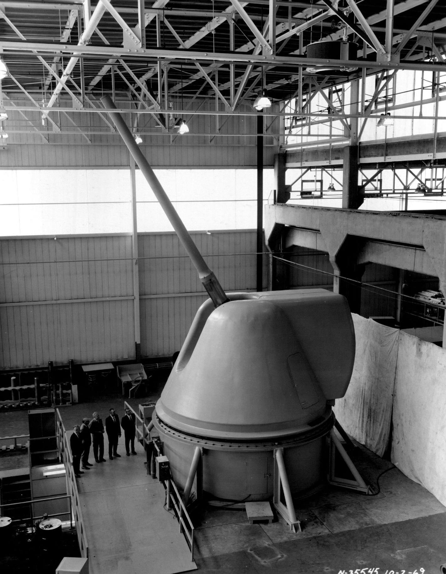 December 11, 1969 Mammoth Gun Mount --- The largest gun mount ordered by the United States Navy since World War II has been designed, developed and produced by the Northern Ordnance Division of FMC Corp. at its Fridley plant. The 175-millimeter, 60-caliber weapon shown here weighs 165,000 pounds. It is now being tested at the plant before delivery to the Naval Weapons Laboratory, Dahlgren, Va. After tests at Dahlgren it will be installed aboard a ship for further test at sea. Dwarfed by their ha