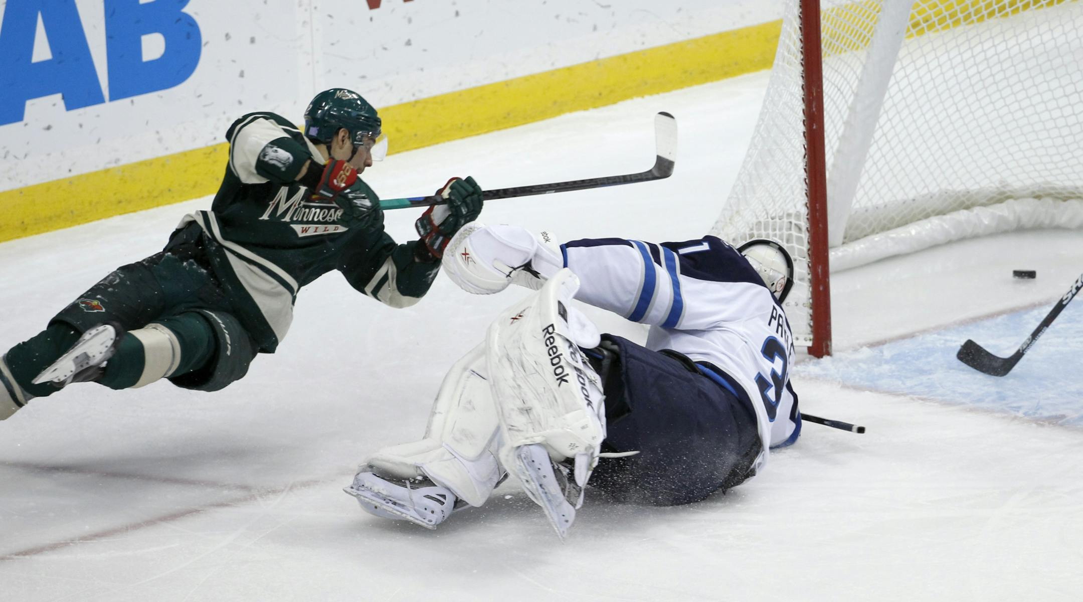 Minnesota Wild right wing Nino Niederreiter, left, of Switzerland, falls as he scores against Winnipeg Jets goalie Ondrej Pavelec, right, of the Czech Republic, during the first period of an NHL hockey game in St. Paul, Minn., Sunday, Nov. 16, 2014.