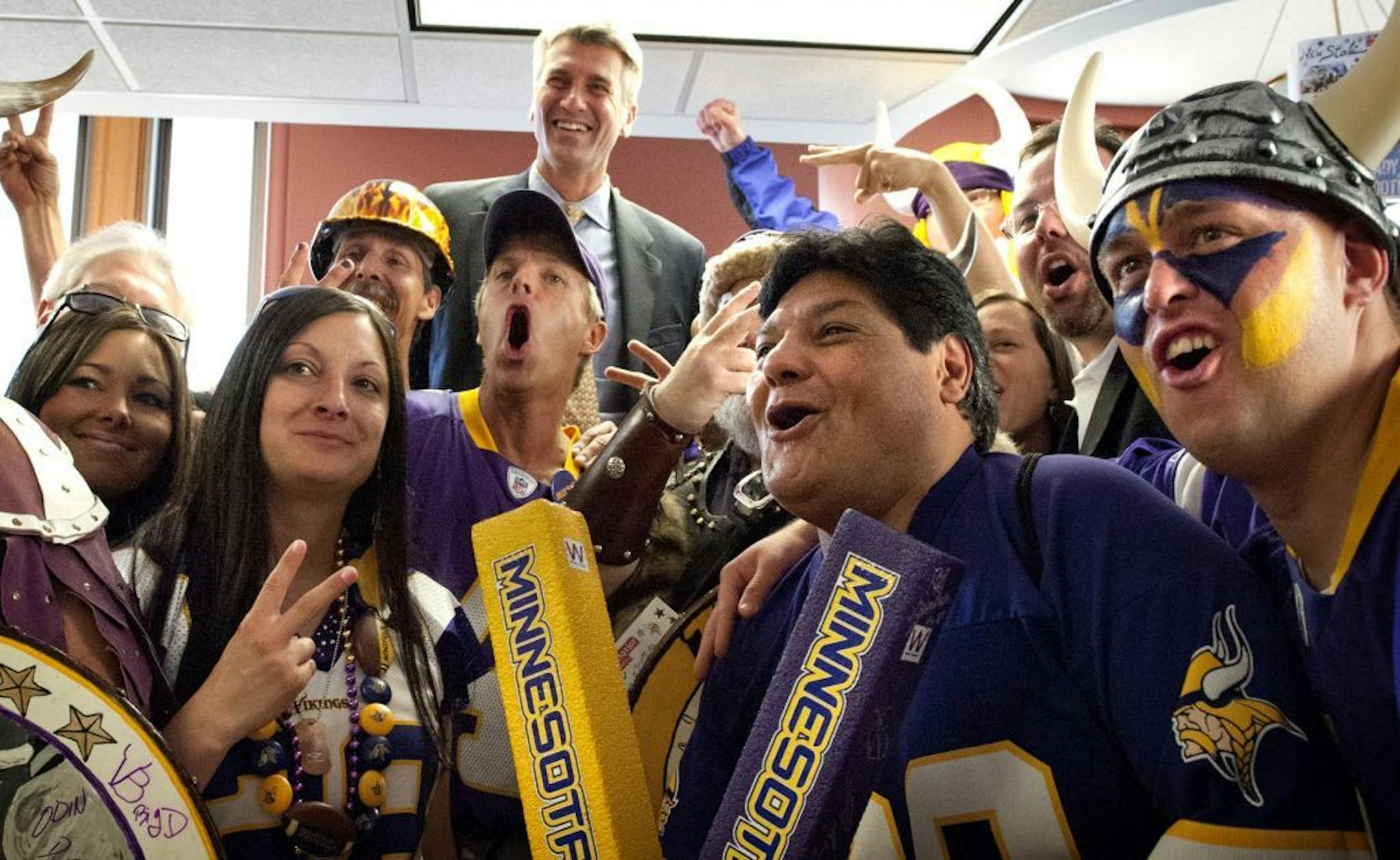Vikings fans gathered in the office of Mayor R.T. Rybak, at rear, to celebrate the Minneapolis City Council vote to build a Vikings Stadium, Friday, May 25, 2012.