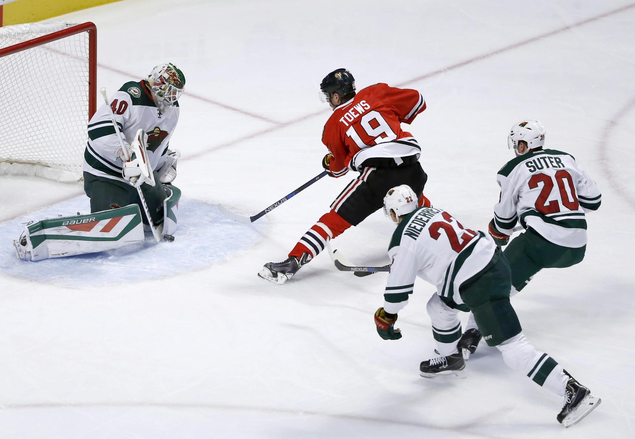 Minnesota Wild goalie Devan Dubnyk makes a save on a point blank shot by Chicago Blackhawks center Jonathan Toews (19) as Nino Niederreiter (22) and Ryan Suter watch during the first period of an NHL hockey game Tuesday, Dec. 1, 2015, in Chicago. (AP Photo/Charles Rex Arbogast)