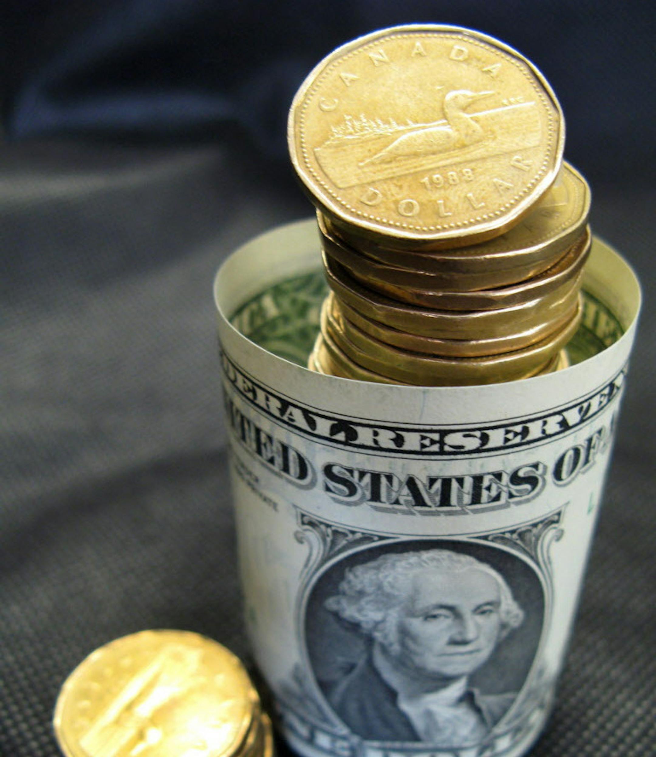 Canadian dollar coins, also known as "loonies," are posed with a U.S dollar bill Tuesday, April 6, 2010, in Montreal. Canada's solid economic fundamentals amid global uncertainty helped push the loonie to parity Tuesday, taking it slightly above US$1 in early morning trading. (AP Photo/The Canadian Press, Ryan Remiorz)