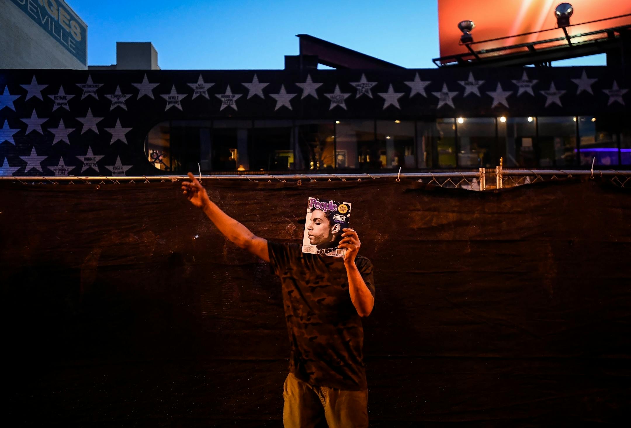 Mark Hamilton, of Memphis, took a break from dancing to hold a People Magazine with a depiction of Prince on it in front of his face Saturday night as he blocked traffic on 7th Street. Hamilton was one of about two hundred fans who took part in their own dance party outside of the barrier enclosing First Ave's block party.
