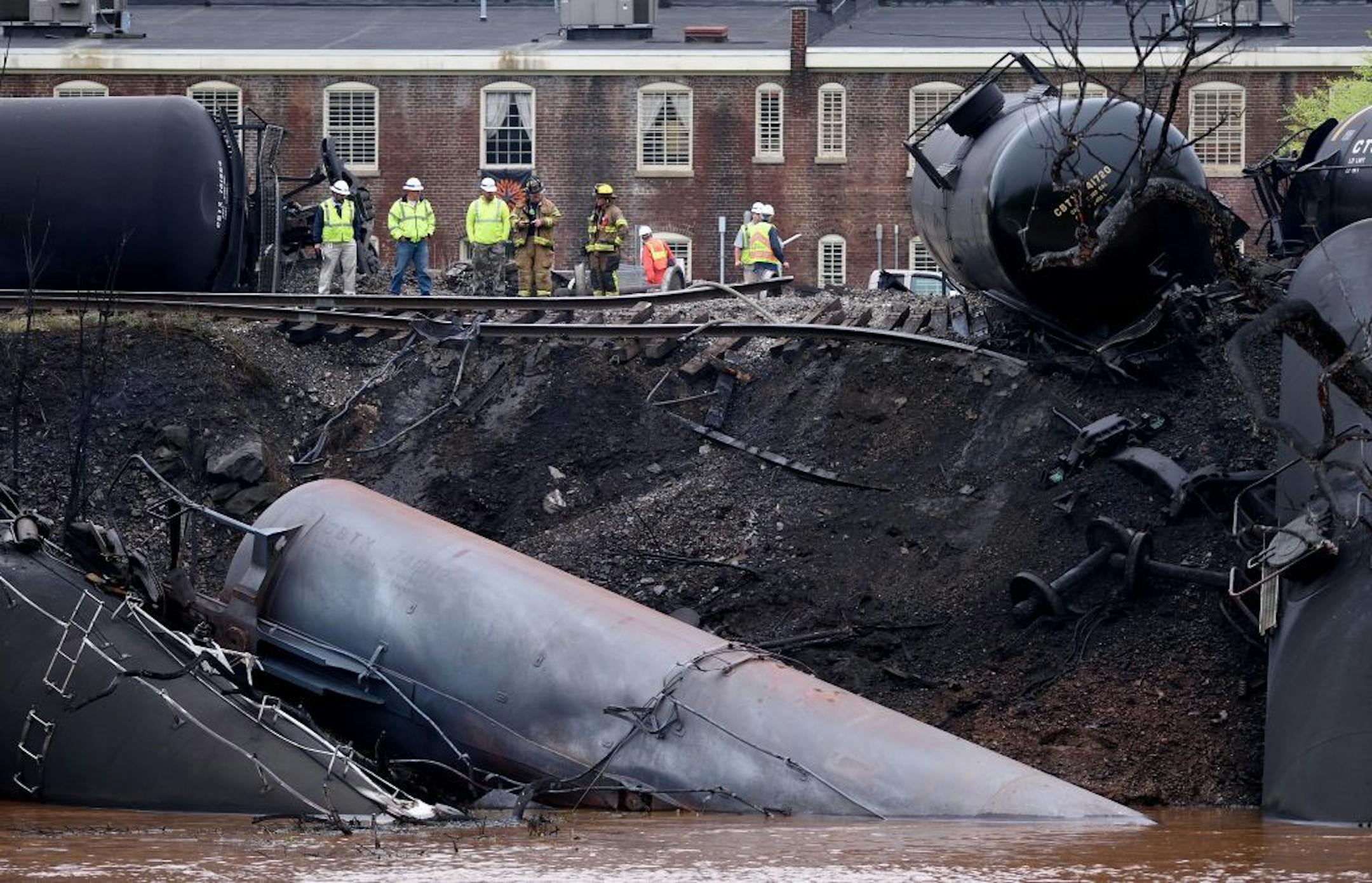 Firefighters and rescue personnel work along the tracks where several CSX tanker cars carrying crude oil derailed and caught fire along the James River in Lynchburg, Va., Wednesday, April 30, 2014.