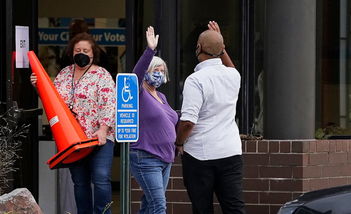 Elliott Payne, the first voter and a candidate for City Council Ward 1, right, gave a high five to fellow voter Jill Davis, the second voter, during the first day of early voting at Minneapolis Elections and Voter Services Friday in Minneapolis. ]