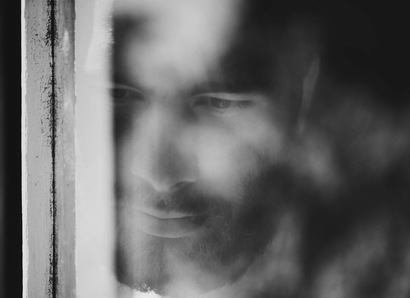 Closeup of a thoughtful young man seen through a window