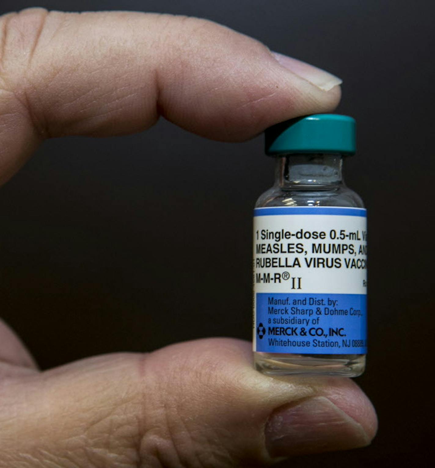 In this Thursday, Jan. 29, 2015 photo, pediatrician Charles Goodman holds a dose of the measles-mumps-rubella, or MMR, vaccine at his practice in Northridge, Calif. The vaccine is 99 percent effective at preventing measles, which spreads easily through the air and in enclosed spaces. Symptoms include fever, runny nose, cough and a rash all over the body. (AP Photo/Damian Dovarganes) ORG XMIT: MIN2015020516451049