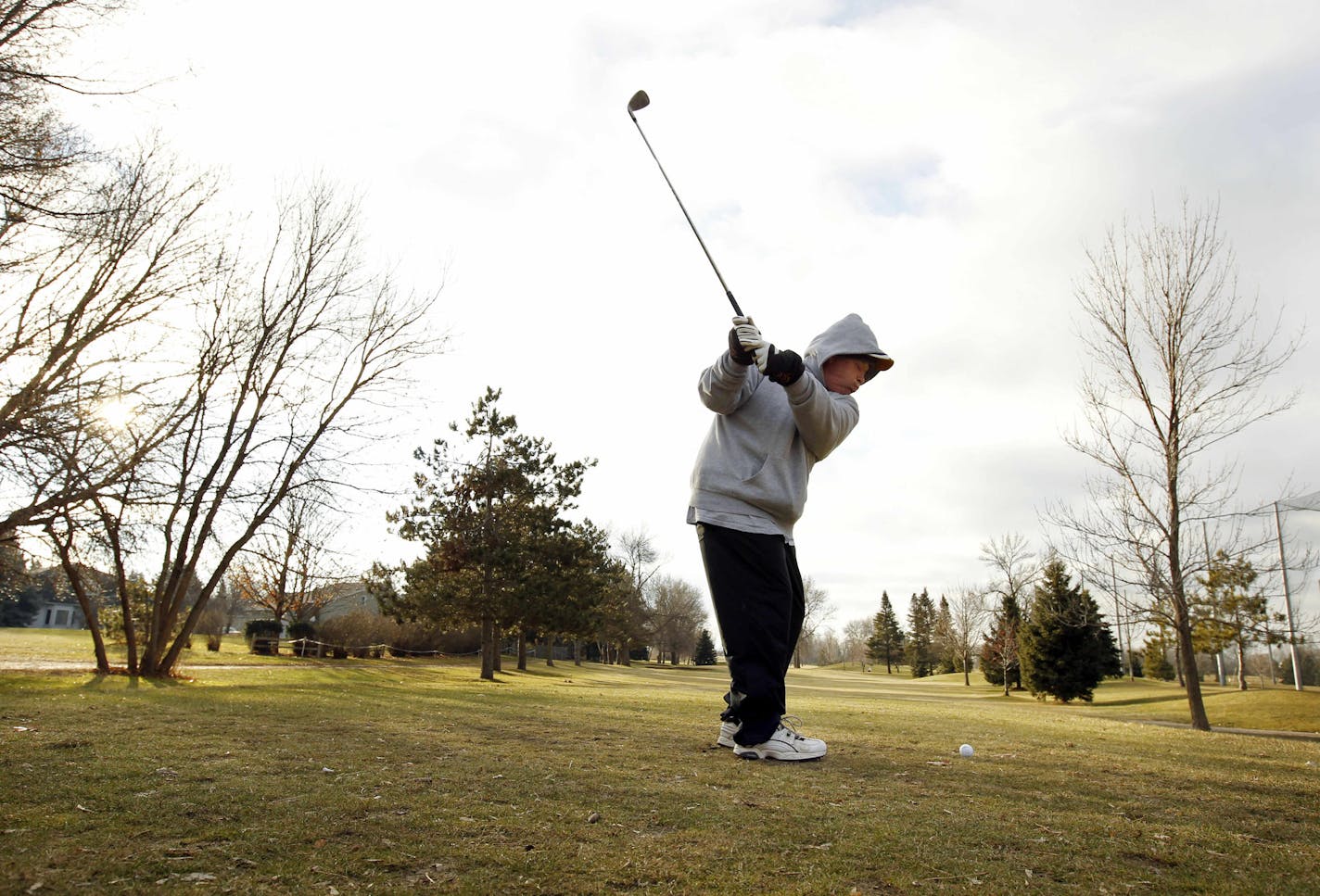 In this Monday, Dec. 19, 2011 photo, with temperatures above freezing and no snow on the ground, Mike Schneider, of St. Paul, Minn., golfs at Parkview Golf Club in Eagan, Minn. From New England to the Dakotas and even parts of the Northern Rockies and Pacific Northwest, snowfall has been well below normal through the fall and early winter with cold air bottled up over Canada. Many downhill ski resorts are making snow to compensate for nature's stinginess. (AP Photo/Genevieve Ross)