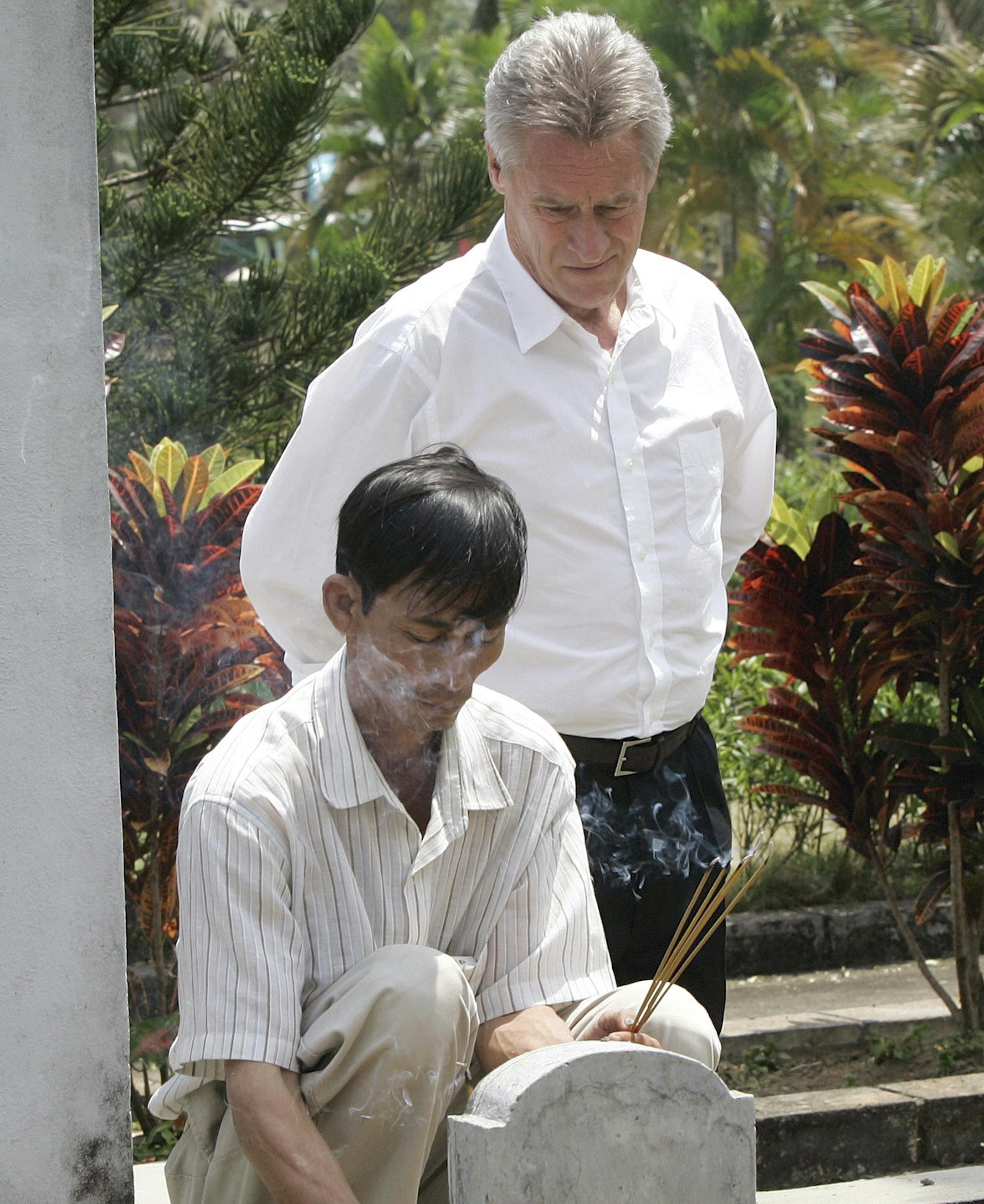 FILE - In this Saturday, March 15, 2008 file photo, My Lai Massacre survivor Do Ba, 48, left, of Ho Chi Minh city, places incense at his family's grave site during the 40 year anniversary of the incident in My Lai, Quang Ngai Province, Vietnam, accompanied by former U.S. Army officer Lawrence Colburn, 58, of Canton, Ga., who rescued Do Ba during the massacre. Colburn, the helicopter gunner who helped end the slaughter of hundreds of unarmed Vietnamese villagers on March 16, 1968, during the Viet