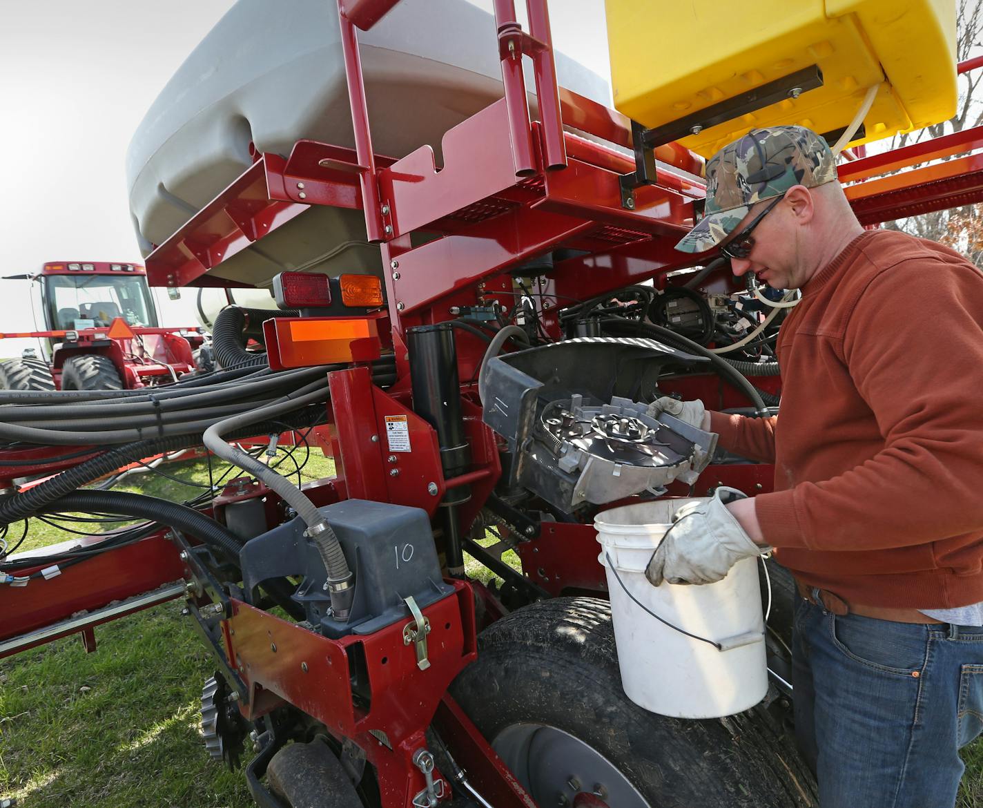 Farmer Marty Amundsen cleaned out seed from throw units on a huge planter attached to a Case STX 325 tractor before planting corn on fields.