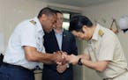 In this June 27, 2016 photo released by the U.S. Coast Guard, Commander Kevin Reed, left, shakes hands with Park Hyog Soo, the South Korean captain of