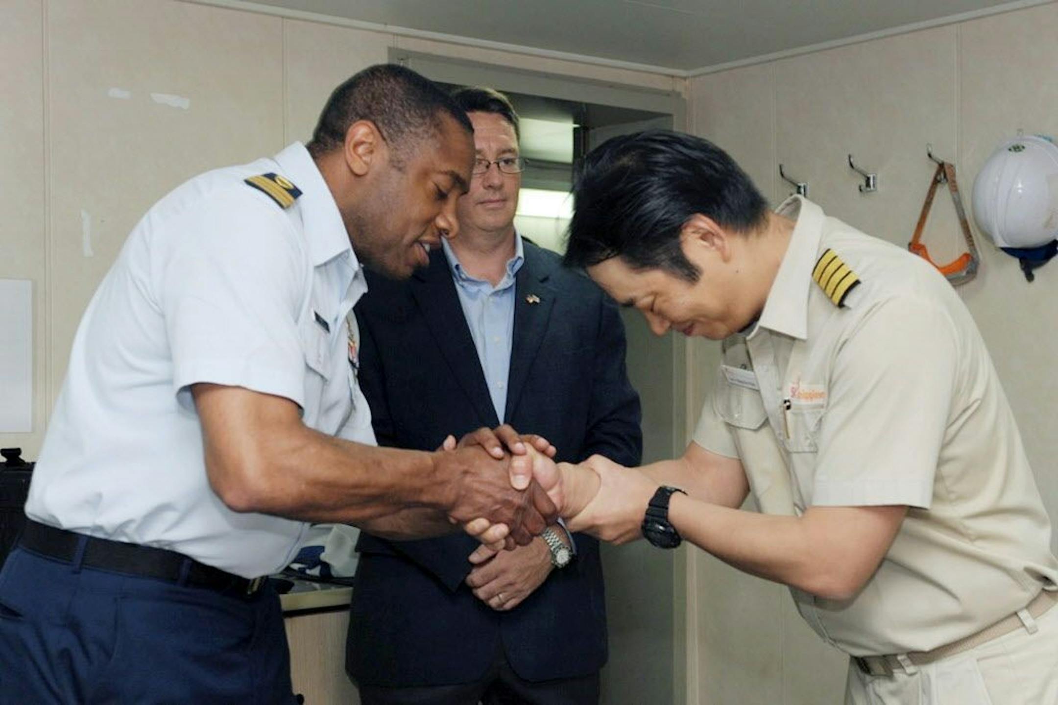 In this June 27, 2016 photo released by the U.S. Coast Guard, Commander Kevin Reed, left, shakes hands with Park Hyog Soo, the South Korean captain of the Panama-flagged cargo ship K. Coral, during an appreciation ceremony in New Haven, Conn. The crew of the K. Coral battled heavy winds and rain to save 19 fishermen who abandoned their burning ship 900 miles southeast of Bermuda in the Atlantic Ocean the previous week. A delegation from the U.S. Coast Guard on Monday thanked the captain and crew
