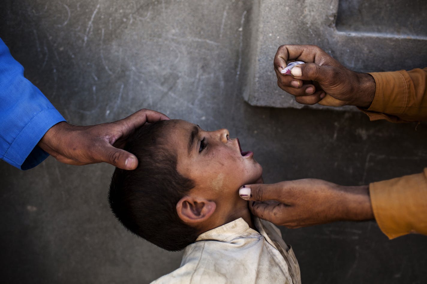 FILE-- Health workers administer a polio vaccine to a child in Jalalabad, Afghanistan, April 22, 2014. The global drive to eliminate polio, which has gone on for 31 years and consumed over $16 billion, has been set back again by a surge of new cases in Pakistan and Afghanistan. As of July 10, 2019, there were a total of 42 polio paralysis cases in the two countries. (Diego Ibarra Sanchez/The New York Times)
