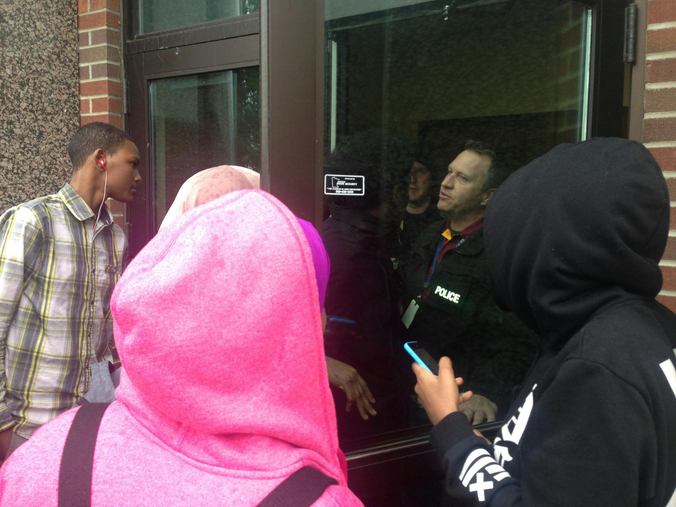 Somali students try to negotiate with a St. Cloud police officer guarding the front door of Tech High School on Friday. The St. Cloud school district has been roiled by tensions between whites and Somali students for the last decade - so much so that it had to reach a settlement with the U.S. Dept. of Ed a few years back - and that reached a boiling point this week. More than 100 Somali students walked out to protest the administration's indifference to their complaints of bullying and harassmen