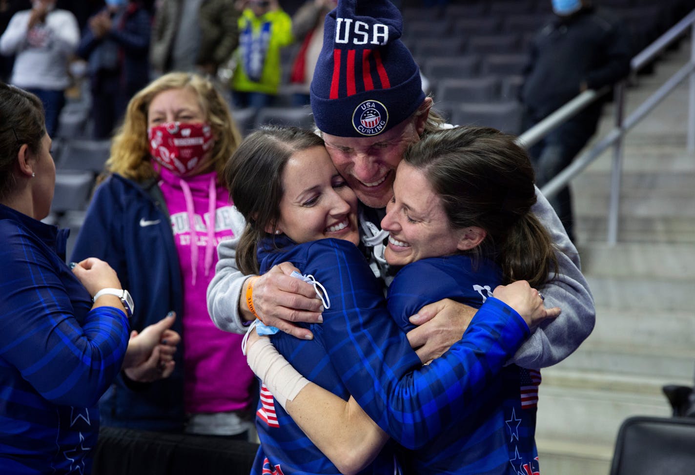 Team Peterson's Tabitha Peterson, left, and Tara Peterson, right, hug their father, Sheldon Peterson, following their victory over Team Christensen during the second night of finals at the U.S. Olympic Curling Team Trials at Baxter Arena in Omaha, Neb., Saturday, Nov. 20, 2021. (AP Photo/Rebecca S. Gratz)