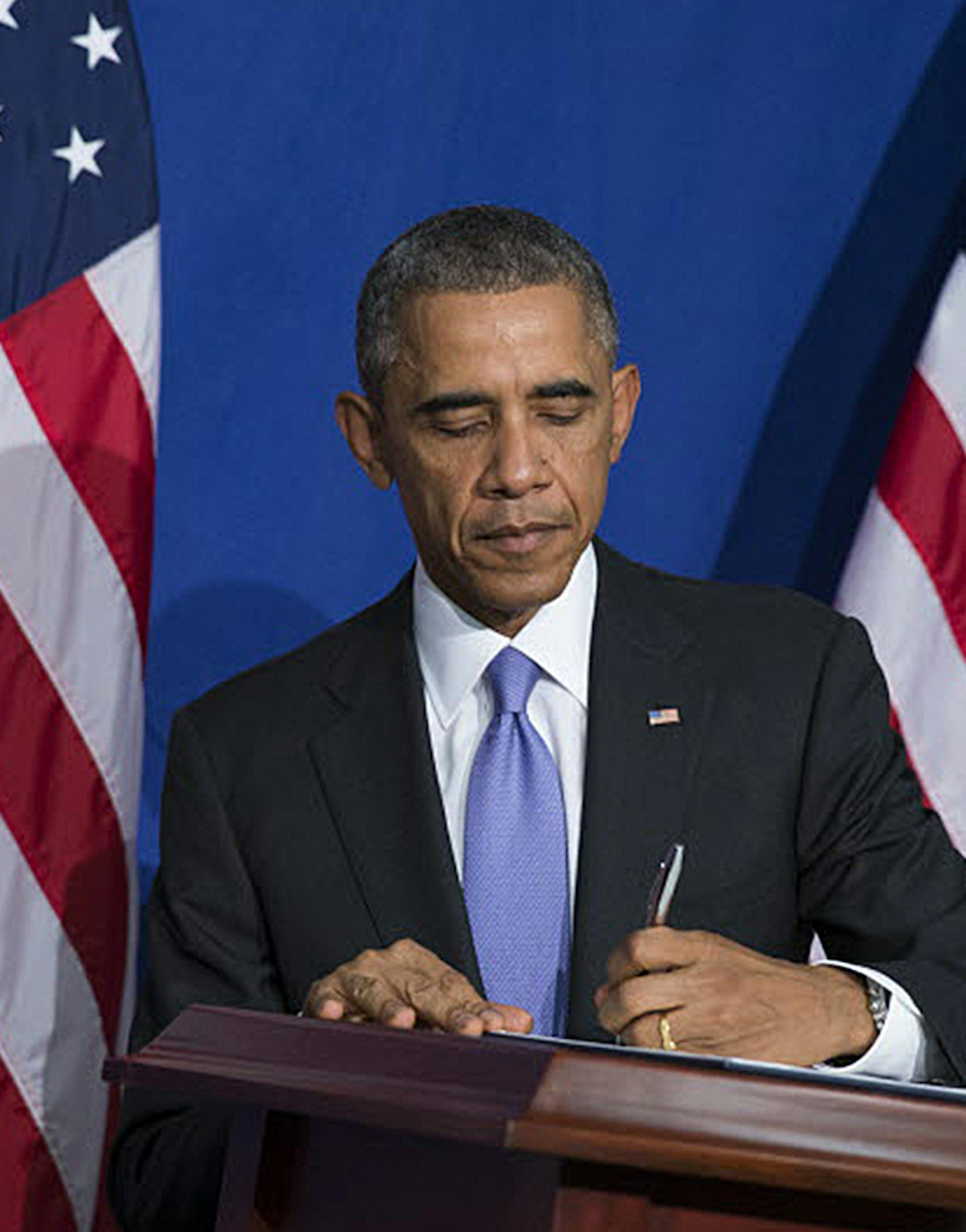 President Barack Obama signs an executive order to improve security measures for government credit and debit cards during an event at the Consumer Financial Protection Bureau, on Friday, Oct. 17, 2014, in Washington. (AP Photo/Evan Vucci)