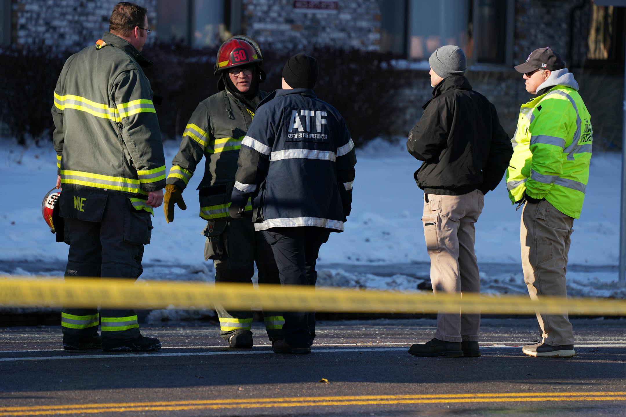 A member of the State Fire Marshal's office, an ATF agent, and Minneapolis fire fighters talk outside the scene of a building fire Saturday, Dec. 3, 2022 in the 2300 block of Lyndale Avenue South in Minneapolis.