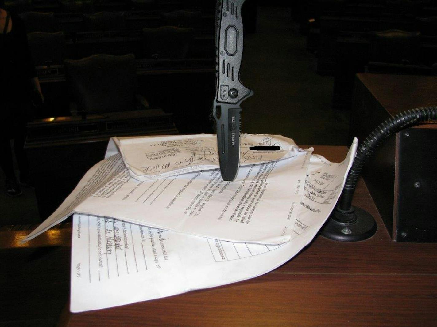 An intruder at the State Capitol pinned these threatening messages on handwritten signs to the clerk's podium using this large knife, according to charges filed Wednesday.