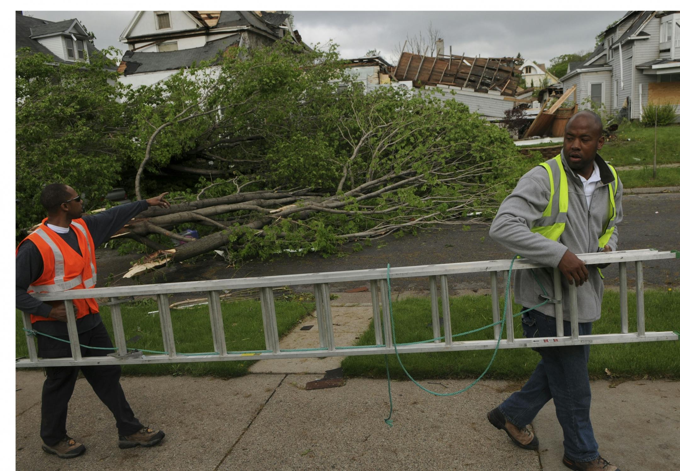 Paul Hill and Jon Rose carried a ladder on Queen Ave N. ,they were going to board up some windows and patch a roof for some family members in North Minneapolis.
