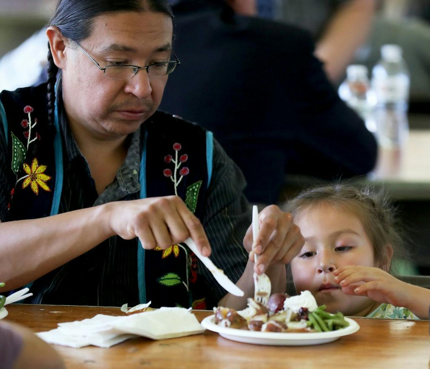 Andy Jackson helped his daughter Luna, 4, cut up her lunch of bison, wild rice, red potatoes, string beans, squash and blueberry dessert after the dedication ceremony for the new Bug-O-Nay-Ge- Shig school in Bena.