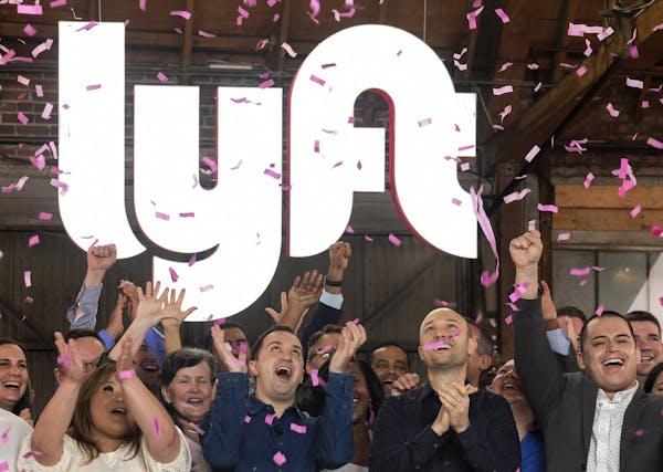Lyft co-founders John Zimmer, front second from left, and Logan Green, front second from right, cheer as they as they ring a ceremonial opening bell i