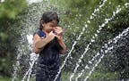 Liana Roman, 5, of Paterson, N.J., stands in the middle of the sprinklers in Eastside Park where temperatures reached the mid-90's on Monday, July 25,