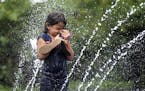 Liana Roman, 5, of Paterson, N.J., stands in the middle of the sprinklers in Eastside Park where temperatures reached the mid-90's on Monday, July 25,