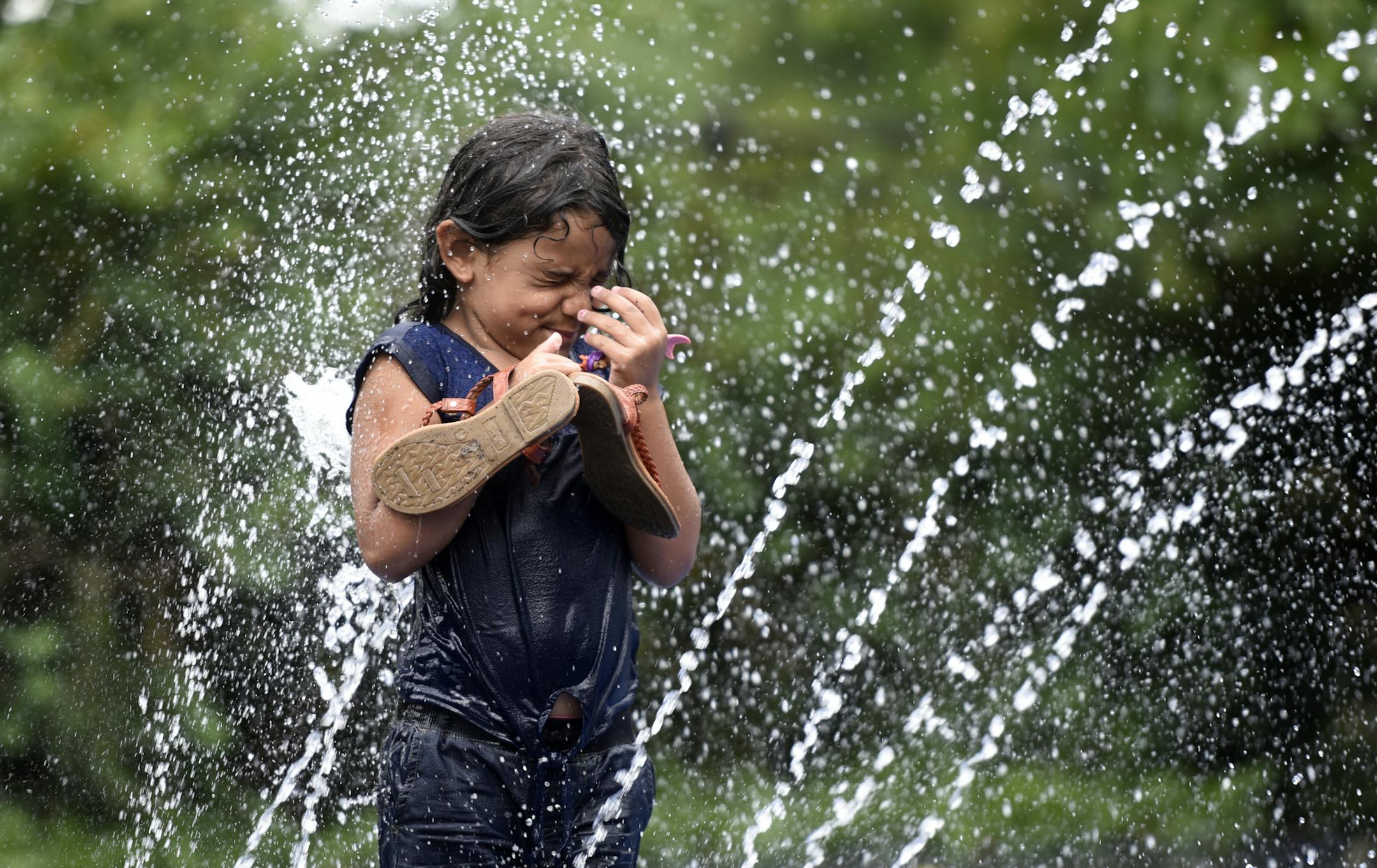 Liana Roman, 5, of Paterson, N.J., stands in the middle of the sprinklers in Eastside Park where temperatures reached the mid-90's on Monday, July 25, 2016, in Passaic, N.J. Sweltering summer weather is in store for New Jersey. Thunderstorms moved through the state earlier on Monday, but did not bring an end to the heat gripping the area. (Danielle Parhizkaran/The Record of Bergen County via AP)