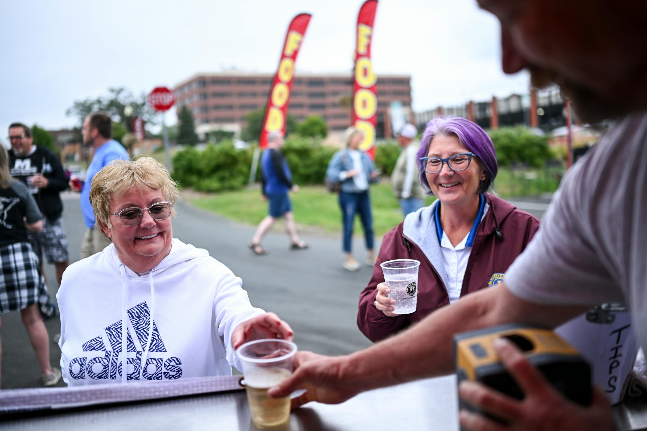 Lisa Olson, of Anoka, is served a glass of chardonnay Wednesday, Sept. 6, 2023 at Riverfront Memorial Park in Anoka, Minn. Starting Wednesday, anybody 21 and older may buy adult beverages from some bars and restaurants in Anoka and consume them as they walk on sidewalks, into shops that allow it, and along the riverfront in the city's historic downtown. The social district will pilot a project as a way to generate activity and bring people together. ] AARON LAVINSKY • aaron.lavinsky@startribune.com