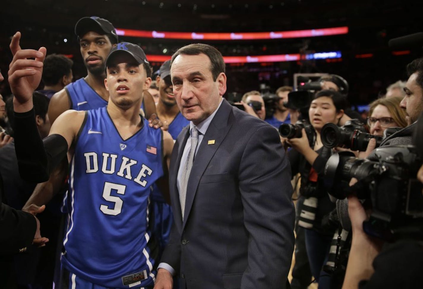 Duke head coach Mike Krzyzewski with Apple Valley's Tyus Jones (5) greets people on the court after an NCAA basketball game against St. John's, Sunday, Jan. 25, 2015 in New York. Duke defeated St. John's 77-68 and Krzyzewski reached his 1,000th career win Sunday.