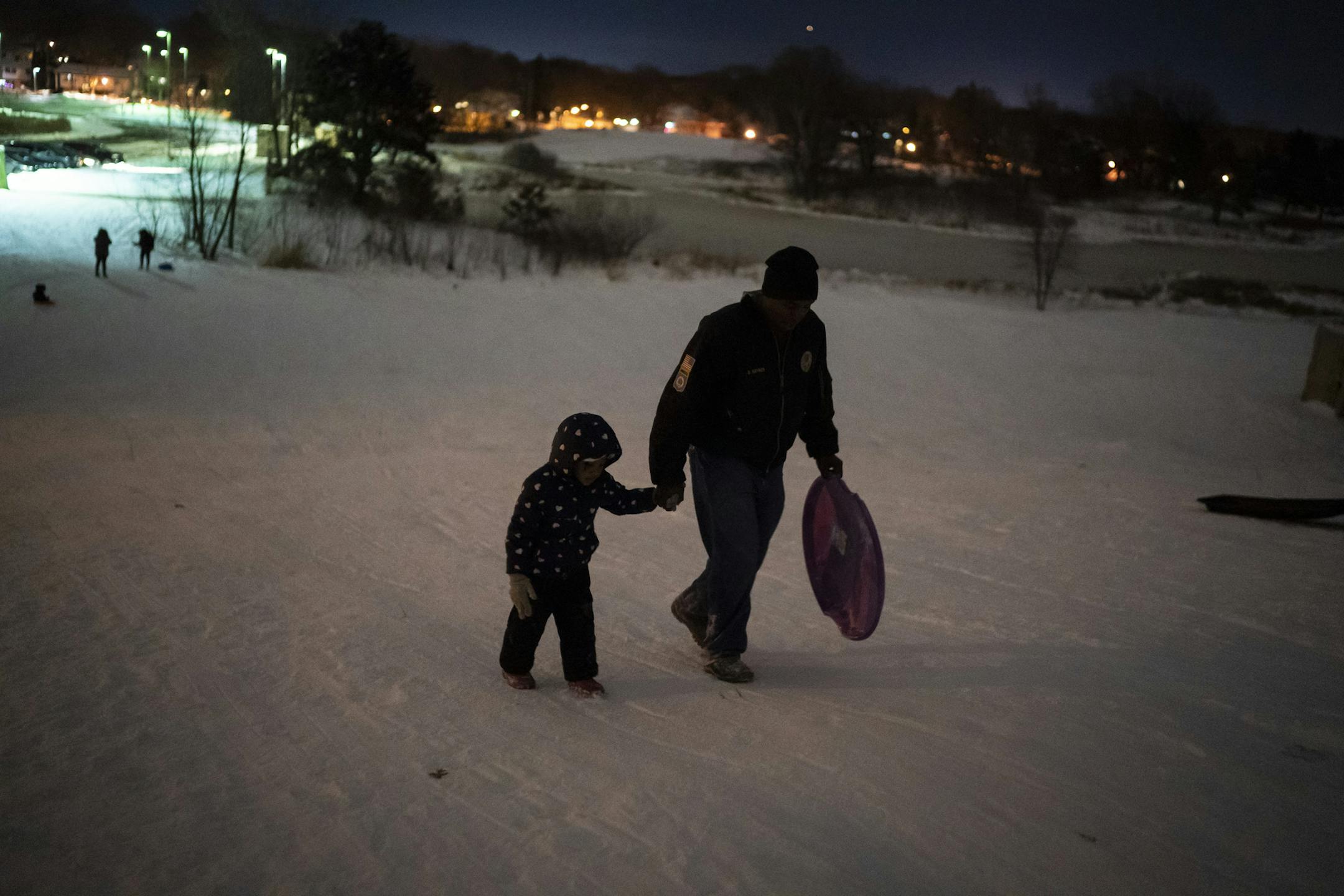 Deonte Haynes walked up a hill holding his daughter Jalei's, 5, hand as he and the family went sledding the night before Haynes headed back to Fort Hood, Texas after a Thanksgiving break before he travels to the Middle East as a helicopter mechanic in the Army National Guard. in St. Paul, Minn., on Monday, December 2, 2019. "I can help you with that," said Haynes to Jalei in regards to carrying her sled. "You can't help me when you're not here," said Jalei sadly. "Well I can help you over the ph
