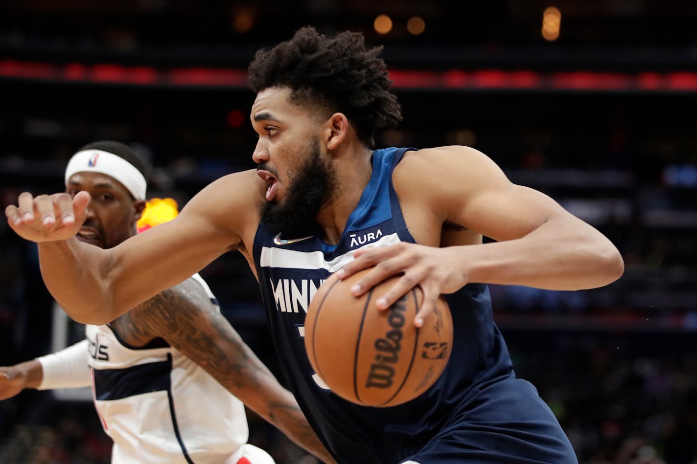 Minnesota Timberwolves' Karl-Anthony Towns, right moves the ball as Washington Wizards' Kentavious Caldwell-Pope, left, defends during the second half of an NBA basketball game Wednesday, Dec. 1, 2021, in Washington. (AP Photo/Luis M. Alvarez)