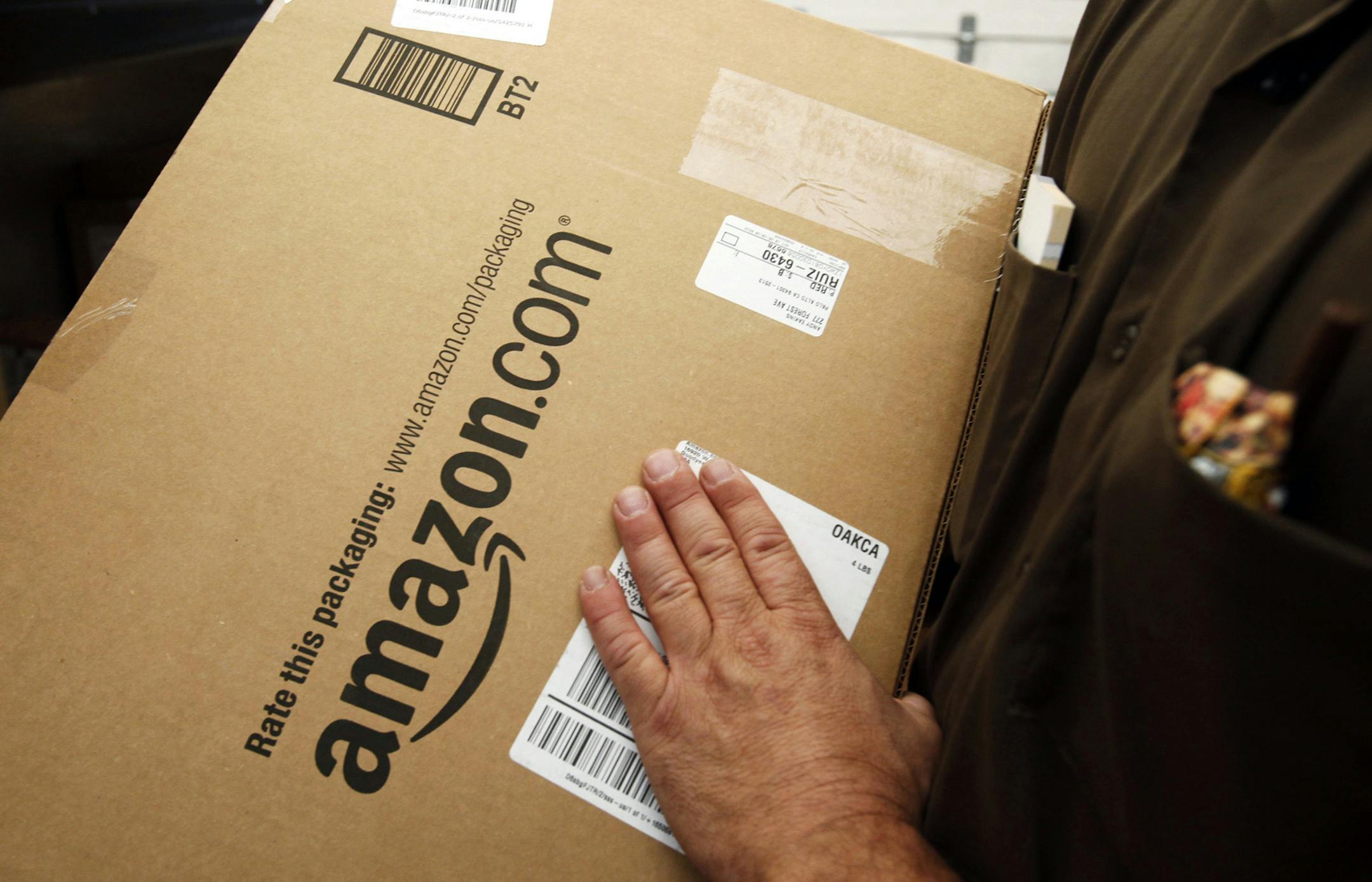 FILE - In this Oct. 18, 2010 file photo, an Amazon.com package is prepared for shipment by a United Parcel Service driver in Palo Alto, Calif. Michigan state legislators in May 2013 are pushing measures to capture the state‚Äôs share of hundreds of millions of dollars in annual taxes from Amazon, eBay and other Internet retailers. Under bipartisan bills being debated in the state House, Internet retailers would have to charge sales tax if they have distribution centers or wareho