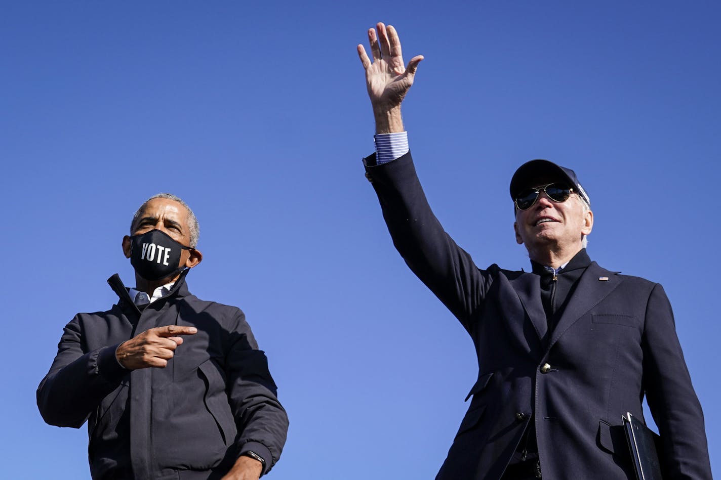 Former U.S. President Barack Obama and Democratic presidential nominee Joe Biden wave to the crowd at the end of a drive-in campaign rally at Northwestern High School on October 31, 2020 in Flint, Michigan. Former Vice President Joe Biden leads Trump by double digits nationally - 54% to 43% according to a daily USC poll. (Drew Angerer/Getty Images/TNS) ORG XMIT: 1814864