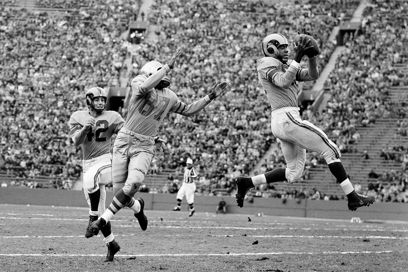 FILE - In this Dec. 7, 1952, file photo, Los Angeles Rams' Dick "Night Train" Lane leaps to intercept a Green Bay Packers pass intended for Packers' end Bob Mann (87), in the second quarter of their game before 35,000 fans in Los Angeles. Other player shown is halfback Herb Rich (42). The hard-hitting cornerback had 68 interceptions in 14 seasons, mostly with the Chicago Cardinals and Detroit Lions in the 1950s and 60s. Lane entered the hall in 1974 and earned his nickname from his teammates from the then-popular song "Night Train" during his first training camp with the LA Rams in 1952. (AP Photo/Harold P. Matosian, File)