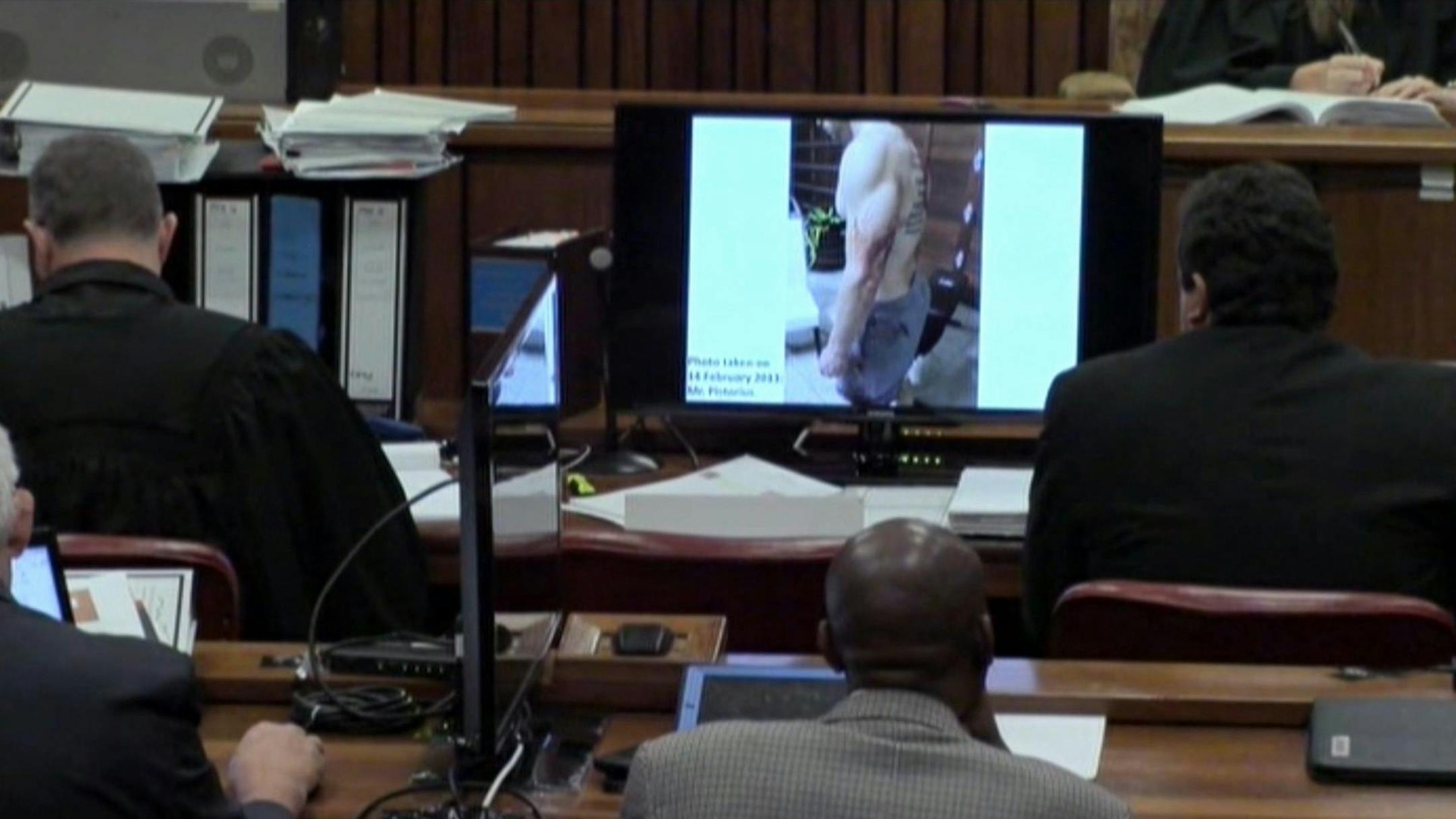 An image taken from the court pool TV via AP showing a police photograph of Oscar Pistorius with blood on his shorts and parts of his body, with a tattoo visible on his back, which was shown to the court in Pretoria, at his murder trial Friday, March 14, 2014.