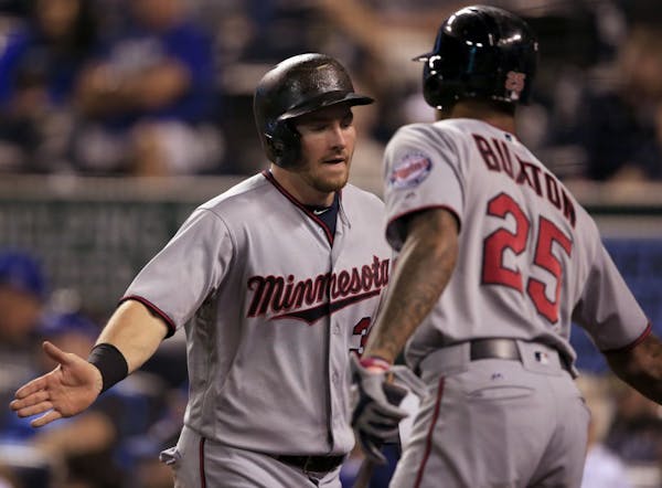 Minnesota Twins' Robbie Grossman, left, is congratulated by teammate Byron Buxton (25) after scoring on a two-run single by Jorge Polanco