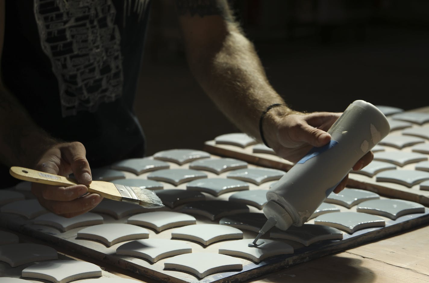 Joel Jannetto applied a second coat of glaze to a tray of Mercury Mosaics' signature Moroccan Fish Scale tiles.