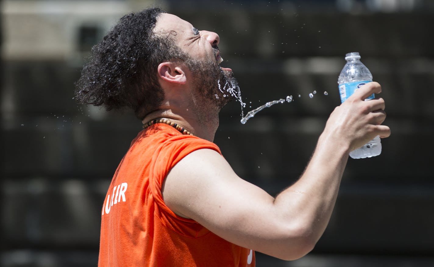 A sweaty Mehdi Kennar poured water on his face during a water break from his world dance workout during the Aquatennial Zumba presented by YWCA in the 90-degree weather at Peavy Park in Minneapolis, Minn., on Friday, July 22, 2016. ] RENEE JONES SCHNEIDER &#x2022; reneejones@startribune.com