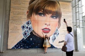 A fan poses in front of a mural of Taylor Swift at Wembley Stadium ahead of her first London concert, during the Eras Tour, in London, Friday June 21,