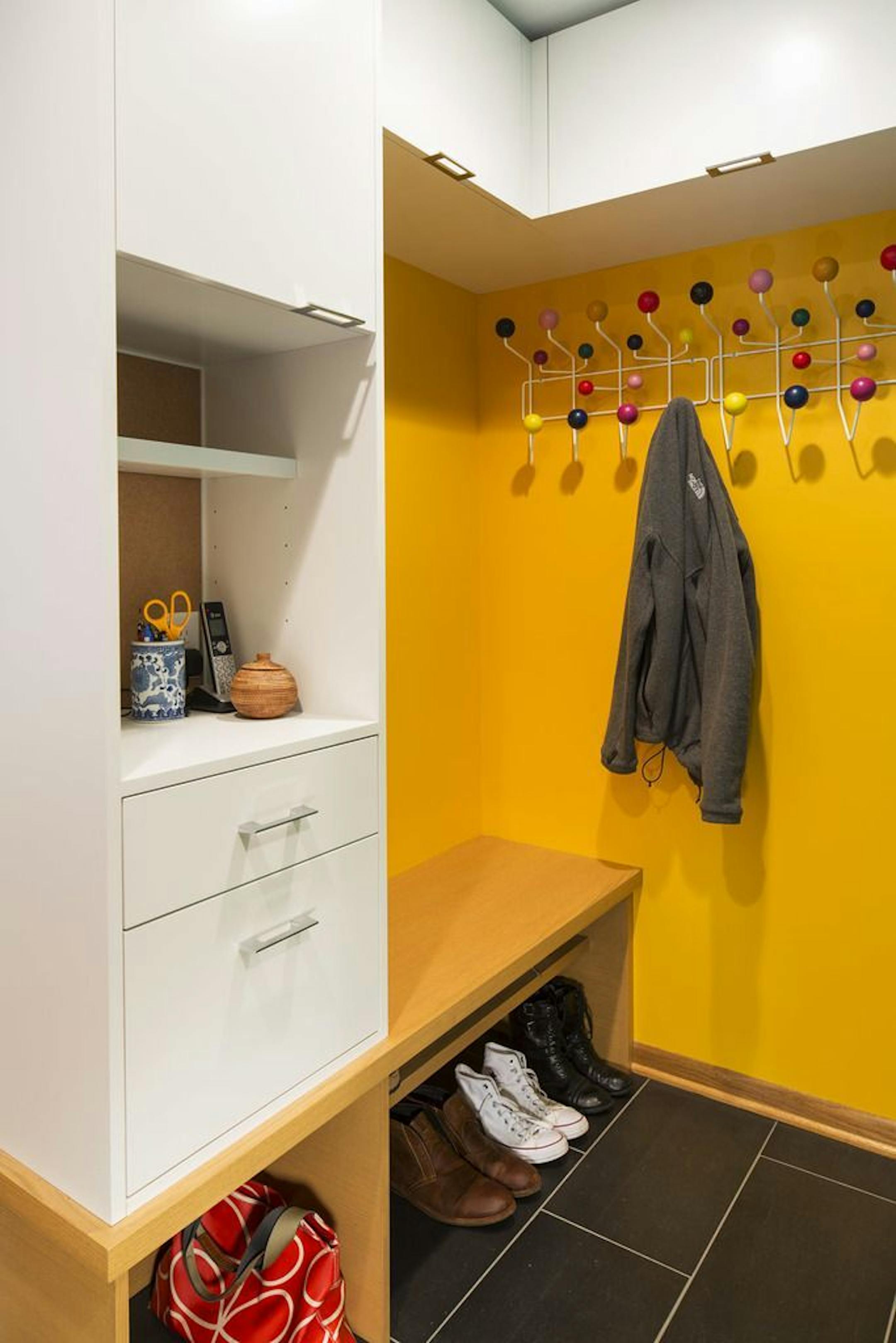 AFTER The yellow mudroom features an Eames Hang-It-All and storage cabinets.